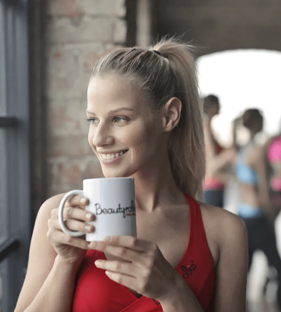Femme blonde souriante en tenue de sport tenant une tasse de café